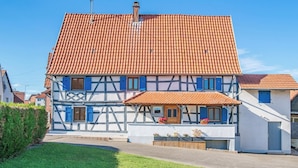 A traditional half-timbered house with a tiled roof and a small porch with potted plants. - La Maison «  Schmoutz 💋 »     Elegant Alsatian house dating from 1752 (Forstheim)