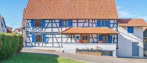 A traditional half-timbered house with a tiled roof and a small porch with potted plants.