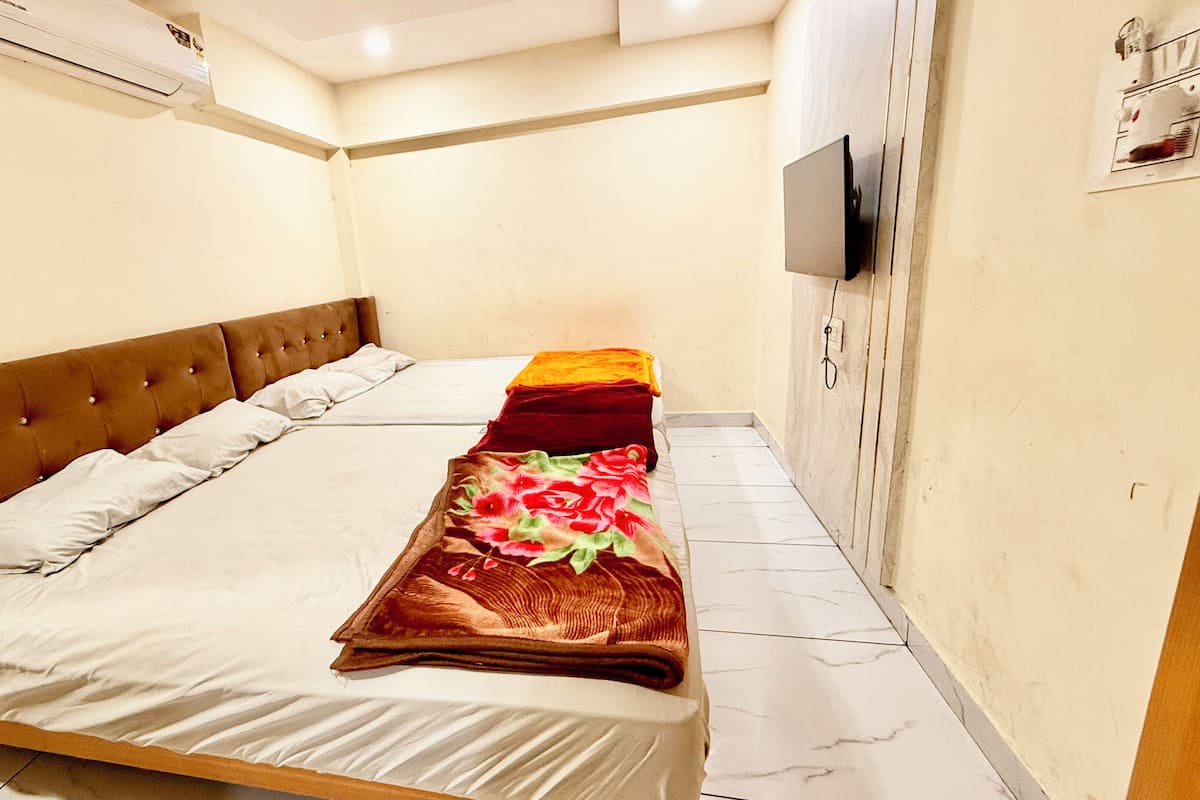 A single bed with a brown headboard, white bedding, and a floral blanket.