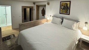 Ein Schlafzimmer mit einem großen Bett, einem Nachttisch, einer Wandlampe und einem Gemälde.