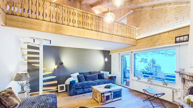 Ett mysigt vardagsrum med ett träpanelat tak, en soffa, ett soffbord och utsikt över omgivningarna.