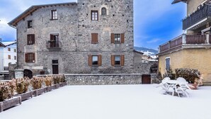A stone building with multiple windows and balconies, surrounded by snow-covered ground and a clear sky. - Beautiful apartment for 5 people with WIFI and TV (Bormio)