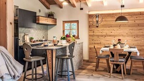 Eine moderne Küche mit Granit-Arbeitsplatten, Holzbalken und einem Essbereich mit einem Holztisch und Stühlen.