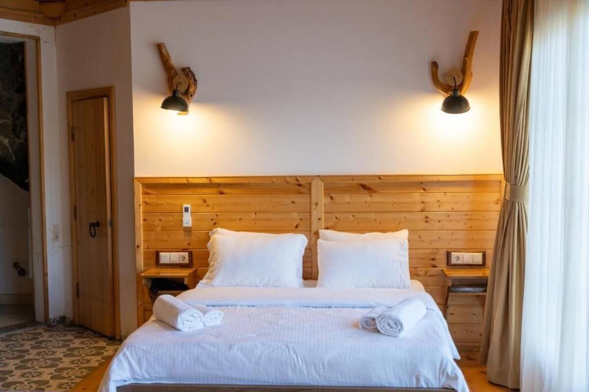 A wooden-paneled bedroom with a double bed, two bedside tables, and wall-mounted lamps.