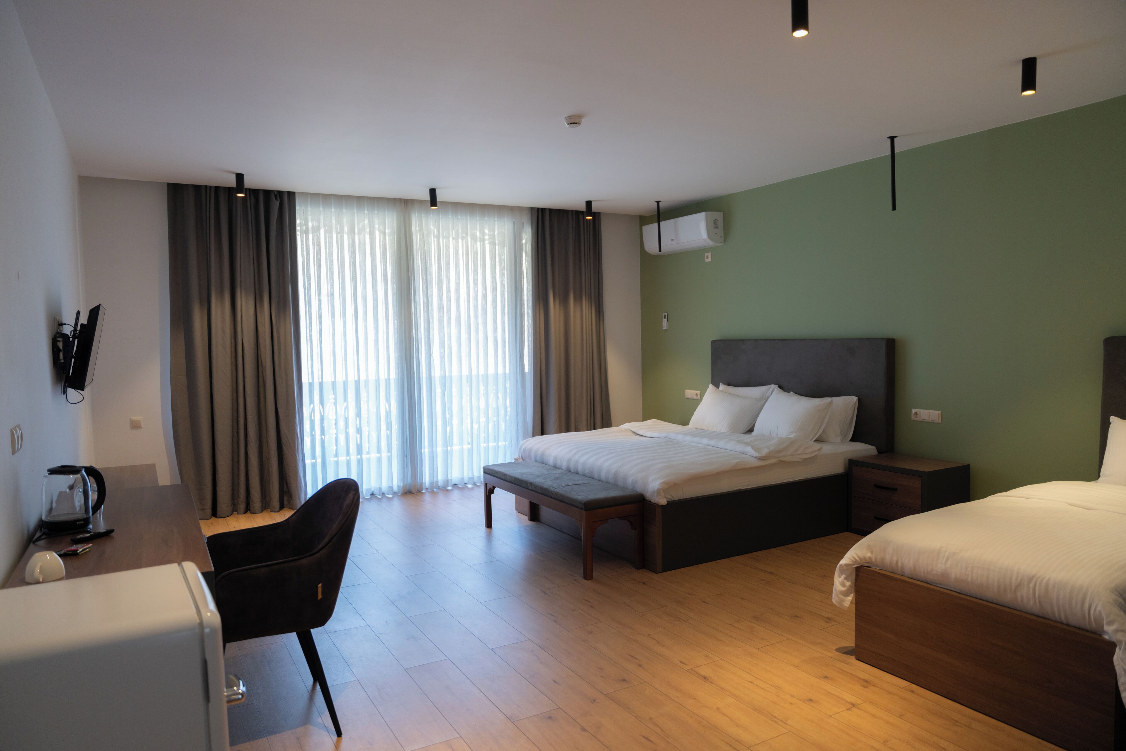 Une chambre d’hôtel avec un lit, un bureau, une chaise et une fenêtre avec des rideaux.