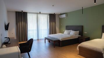 Une chambre d’hôtel avec un lit, un bureau, une chaise et une fenêtre avec des rideaux.