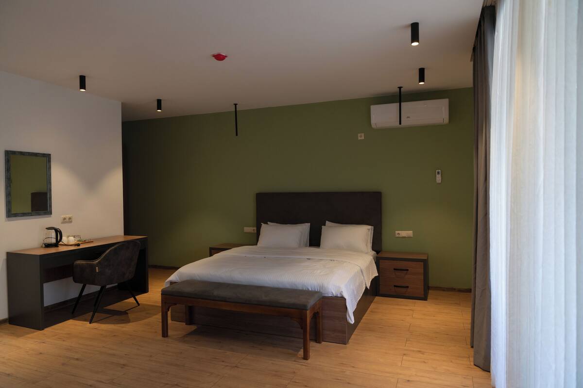 A bedroom with a bed, bedside tables, a desk, and a chair.