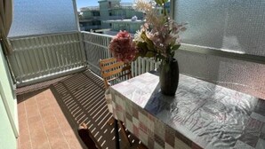 Un balcon avec une nappe à carreaux, un banc en bois et un vase rempli de fleurs.