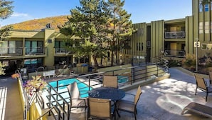 Un hotel con piscina, mobiliario exterior y vistas a una colina.