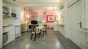 A compact kitchen with white cabinetry, a dining table with chairs, a television, and a red-framed picture on the wall. - Absolute Center, Parking - (Private Museum) (Mantova)