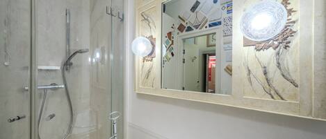 A bathroom with a glass-enclosed shower, a sink with a mirror above it, and a decorative wall piece.