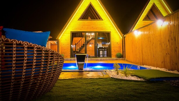 Una casa de madera con piscina, una escalera y exterior bien iluminado.