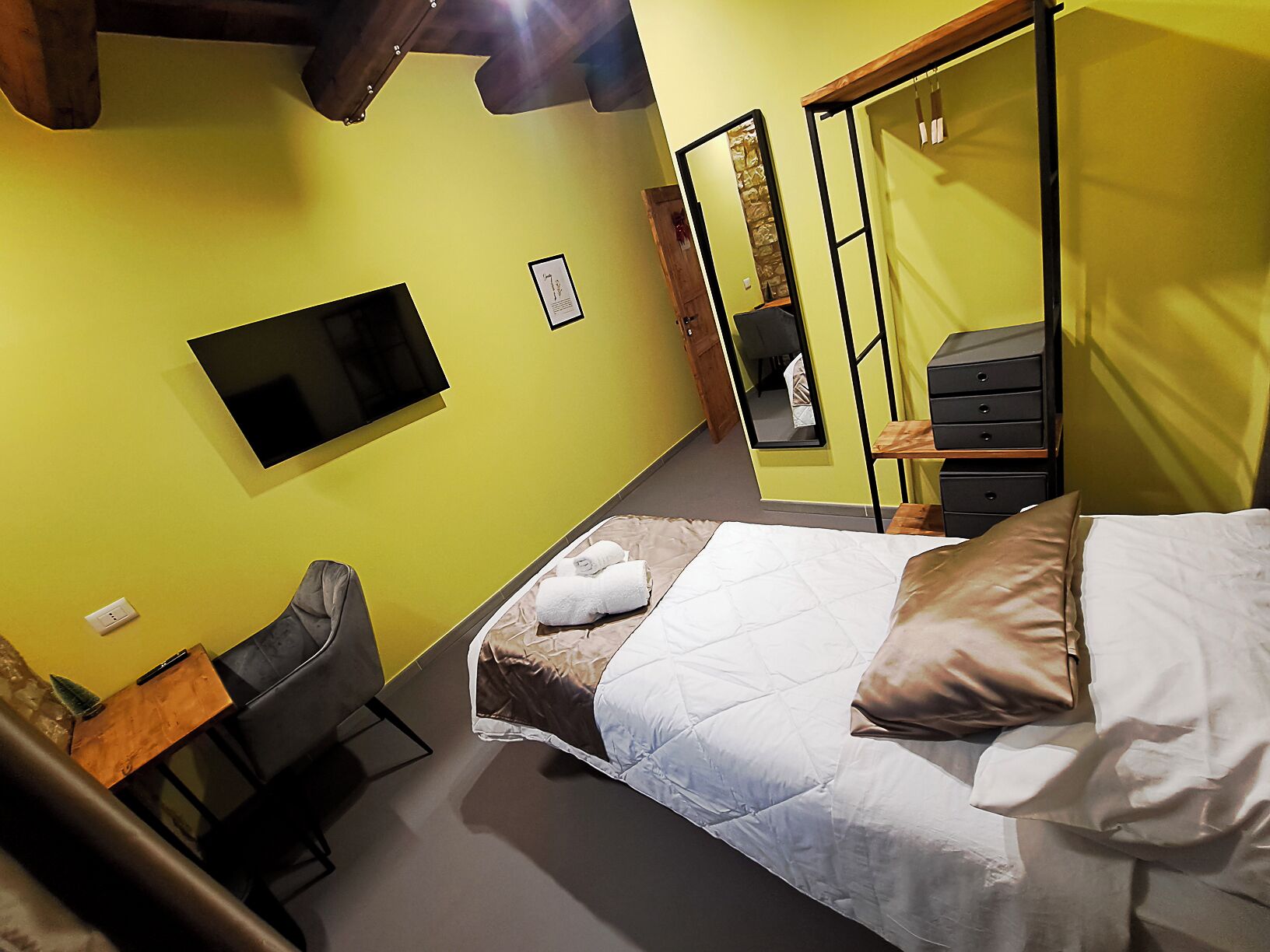 Una habitación de hotel con cama, escritorio, silla, televisor y armario.