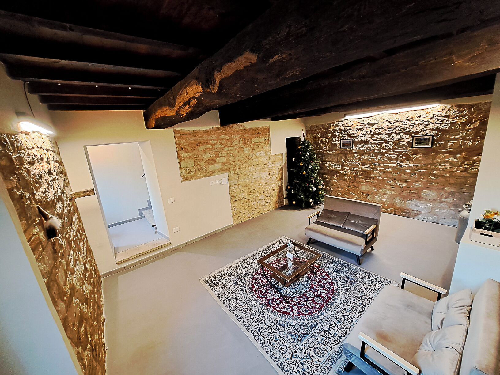 A cozy living room with a stone wall, a fireplace, a sofa, and a coffee table.