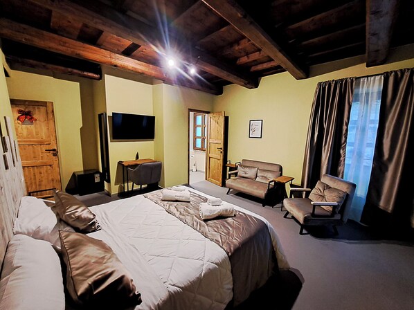 A hotel room with a large bed, a desk with a chair, a sofa, and a TV mounted on the wall. - IL MOLINO DEL SIGNORE (Pergola)