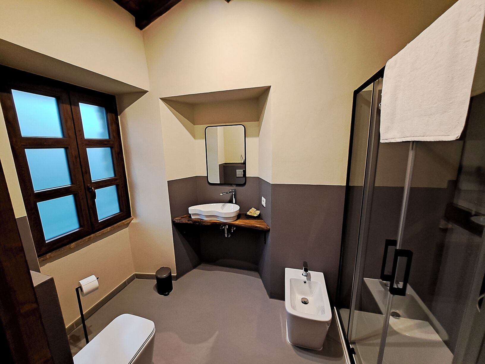 Un baño moderno con inodoro, lavamanos, espejo y ducha.