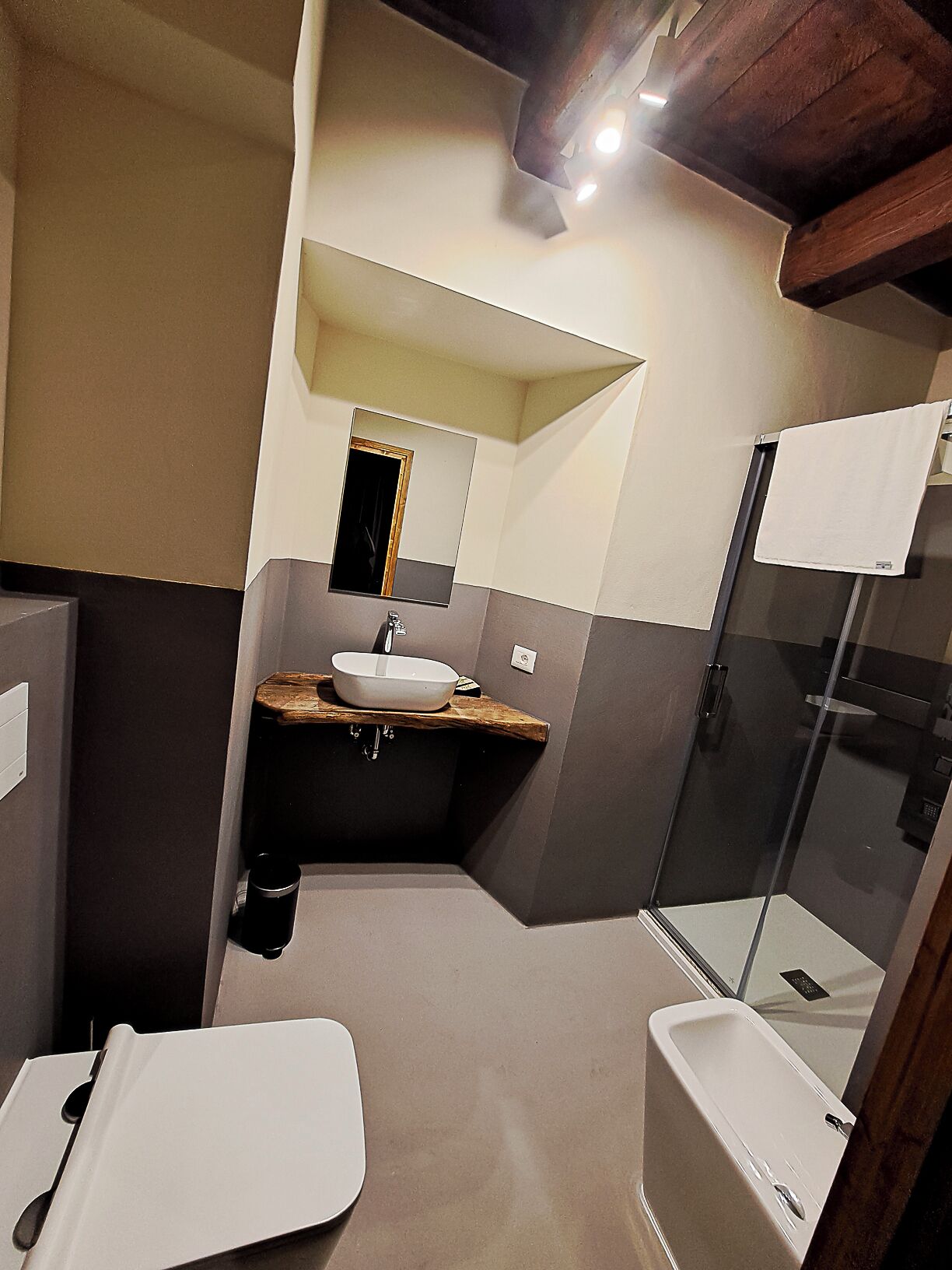 Un baño moderno con un lavabo grande, un espejo y una ducha con mampara de vidrio.