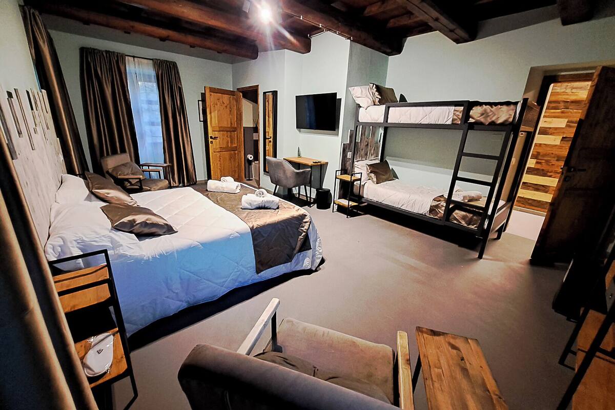 Una habitación con literas, un escritorio, una silla, un televisor y una ventana con cortinas.