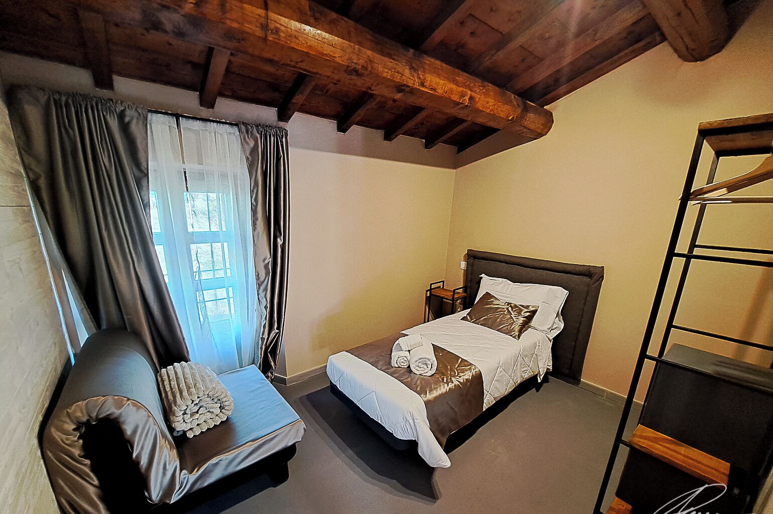 Un dormitorio con una cama, una silla y techo de madera.