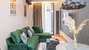 Een moderne woonkamer met een groene modulaire bank, een marmeren salontafel en een bijzondere hanglamp van rots.