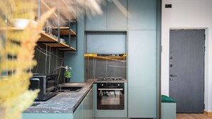 Een moderne keuken met inbouwapparatuur, houten vloeren en een grijze deur.