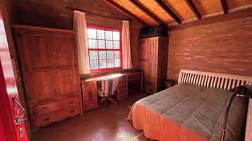 Una habitación rústica de madera con una cama, un escritorio y una ventana con cortinas.