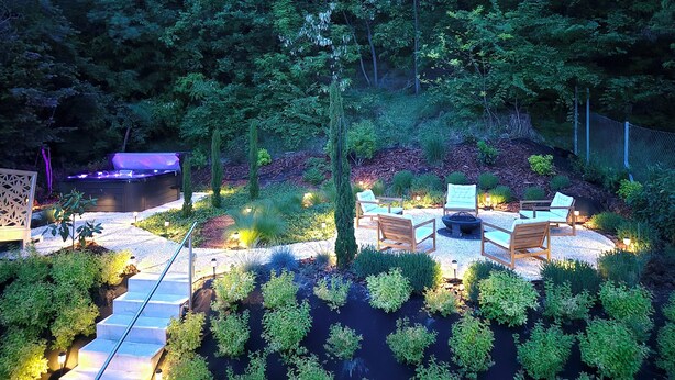 A garden with a fire pit, seating area, and a hot tub.