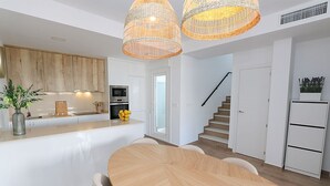 Una cucina moderna con mobili bianchi, un'isola centrale e un'area pranzo con tavolo e sedie in legno.