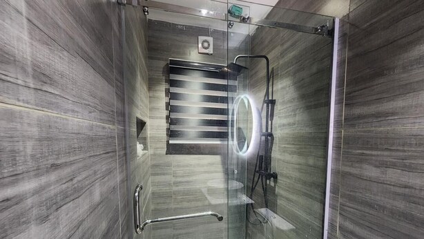 Un baño moderno con cabina de ducha de vidrio, barra de apoyo y toallero visible.