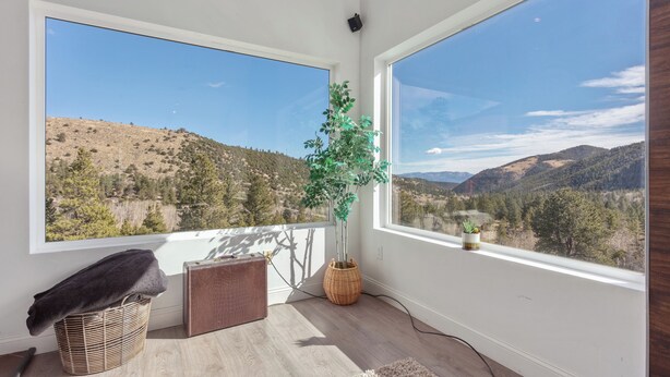 Quarto com amplas janelas que oferecem vista para uma paisagem montanhosa.