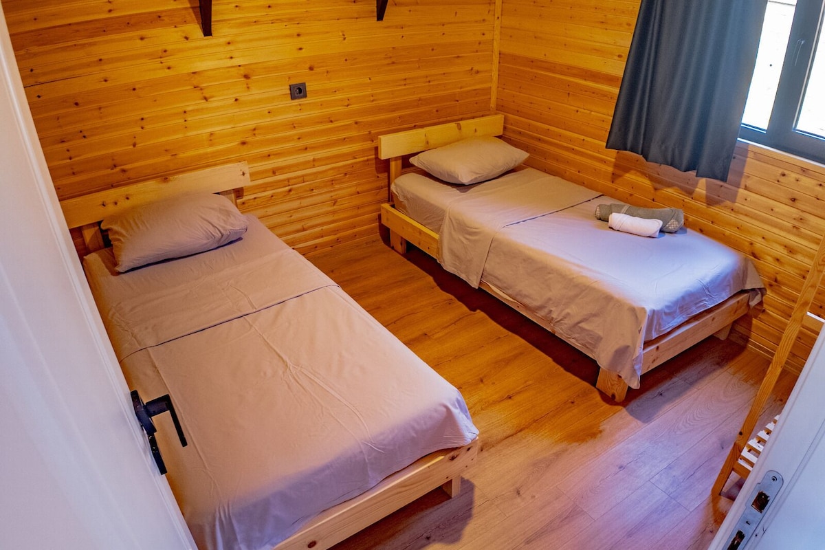 A cabin with two wooden beds, each with a pillow and a blanket.