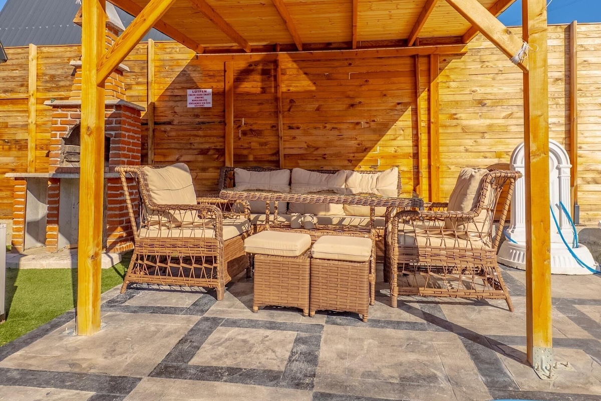 A covered outdoor seating area with wicker furniture and a brick fireplace.
