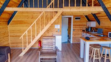 A wooden interior with a loft bedroom, a kitchen area, and a staircase.