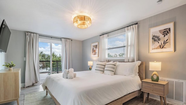 Un dormitorio moderno con una cama grande, lámparas de noche, un televisor y vistas al exterior.