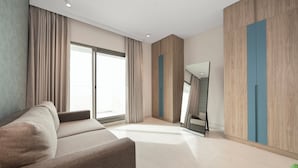 A modern hotel room with a sofa, a large mirror, and a wardrobe with a blue accent. - Tranquil Wellness Hotel Apartments (Dubai)