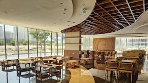 A spacious indoor area with multiple seating arrangements, large windows, and a modern ceiling design. - Tranquil Wellness Hotel Apartments (Dubai)