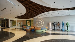 A modern lobby with a curved marble floor, a wooden ceiling, and colorful seating areas. - Tranquil Wellness Hotel Apartments (Dubai)