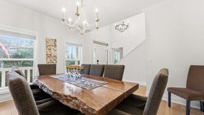 A dining area with a large wooden table, upholstered chairs, and a chandelier. - Forget-Me-Not: Spacious 6-Bedroom Retreat, Walk to Downtown (Highlands)