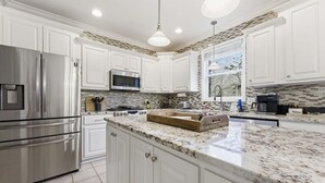 A modern kitchen with white cabinets, stainless steel appliances, a granite countertop, and a window with a view. - Forget-Me-Not: Spacious 6-Bedroom Retreat, Walk to Downtown (Highlands)