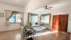 A living room with a sofa, armchairs, a coffee table, and a wooden door. - 3-bedroom ocean front bungalow in delightful Long Bay, Portland w AC ,Ocean View (Long Bay)