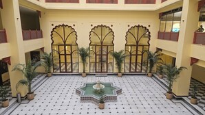 Un patio con una fuente, plantas en macetas y suelo a cuadros.
