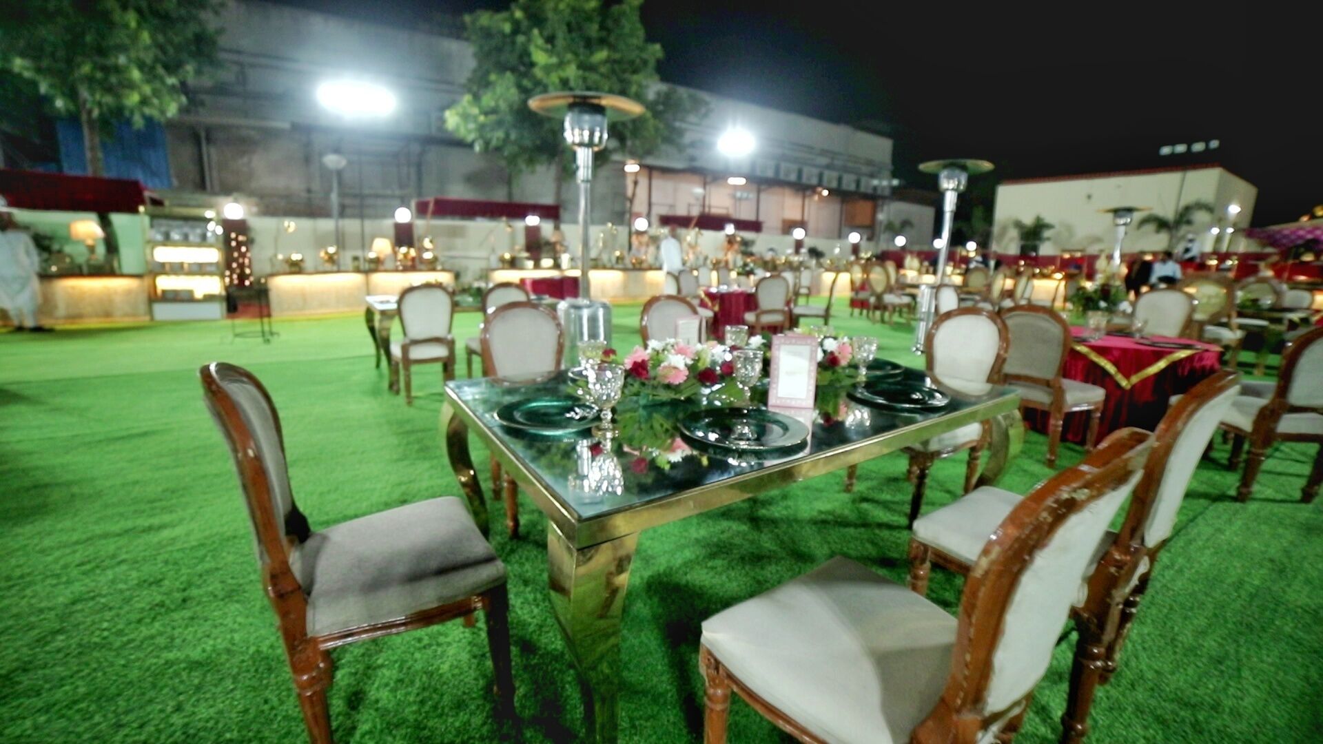 An outdoor dining area with tables set for a meal, surrounded by chairs.