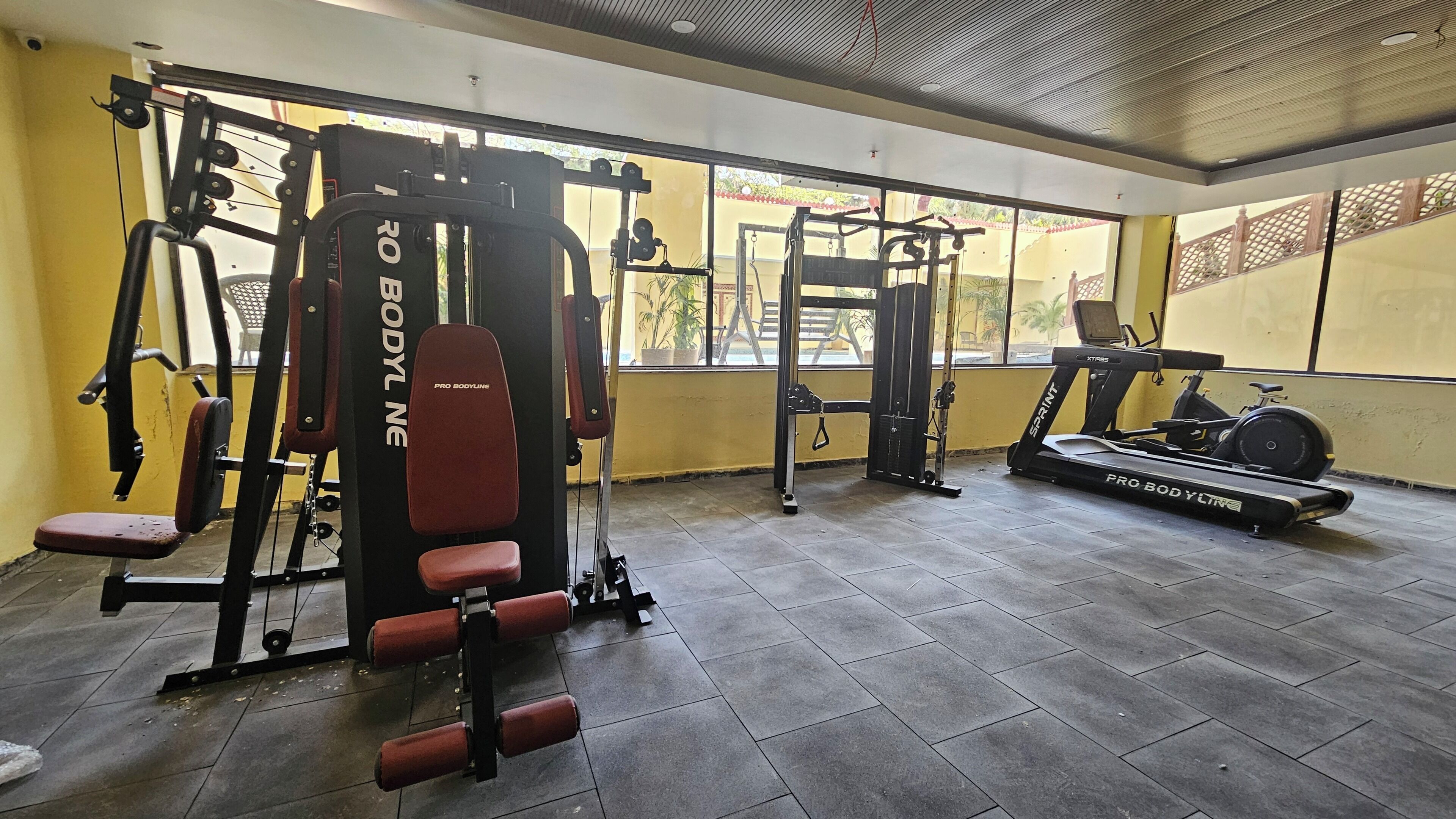 Una palestra con diverse attrezzature per l'allenamento, tra cui una panca per squat, una pressa per bilanciere e tapis roulant.
