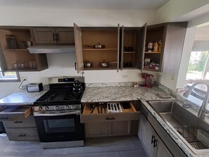 A kitchen with a stove, oven, and open cabinets. - A quiet cabin in the country. (Duluth)
