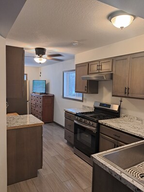 A modern kitchen with granite countertops, stainless steel appliances, and wooden cabinets. - A quiet cabin in the country. (Duluth)