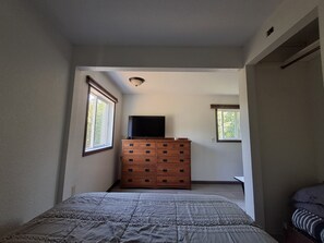 Une chambre à coucher avec un lit, une commode et deux fenêtres.