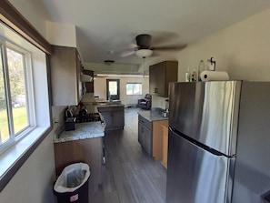 A modern kitchen with a stainless steel refrigerator, granite countertops, and a ceiling fan.