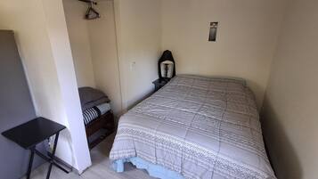 Une chambre à coucher avec un lit, une table de chevet, une lampe, une armoire et une petite table.