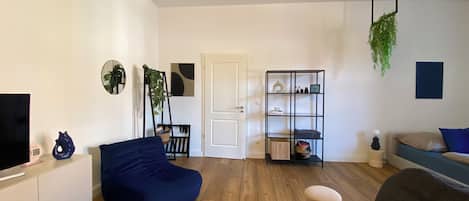 A modern living room with a sofa, a TV, a bookshelf, and a door.