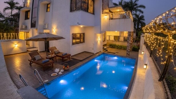 A modern two-story house with a swimming pool, outdoor seating, and string lights. - Aarna Villa nr Valvan Dam (Lonavala)